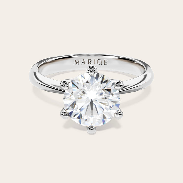Eterna moissanite solitaire ring front view on tan background
