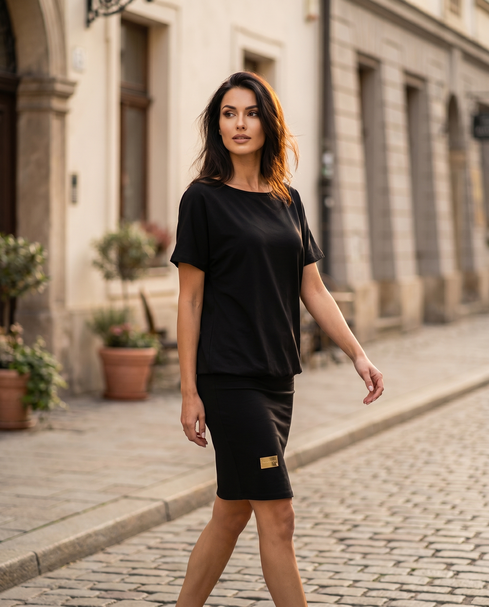 Woman wearing the black Melissa relaxed stretch dress, walking on a sunlit street