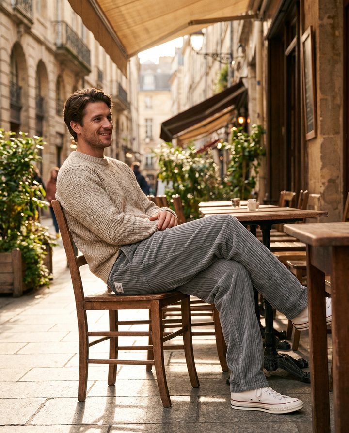 Man wearing Monaco corduroy trousers seated at a cafe terrace