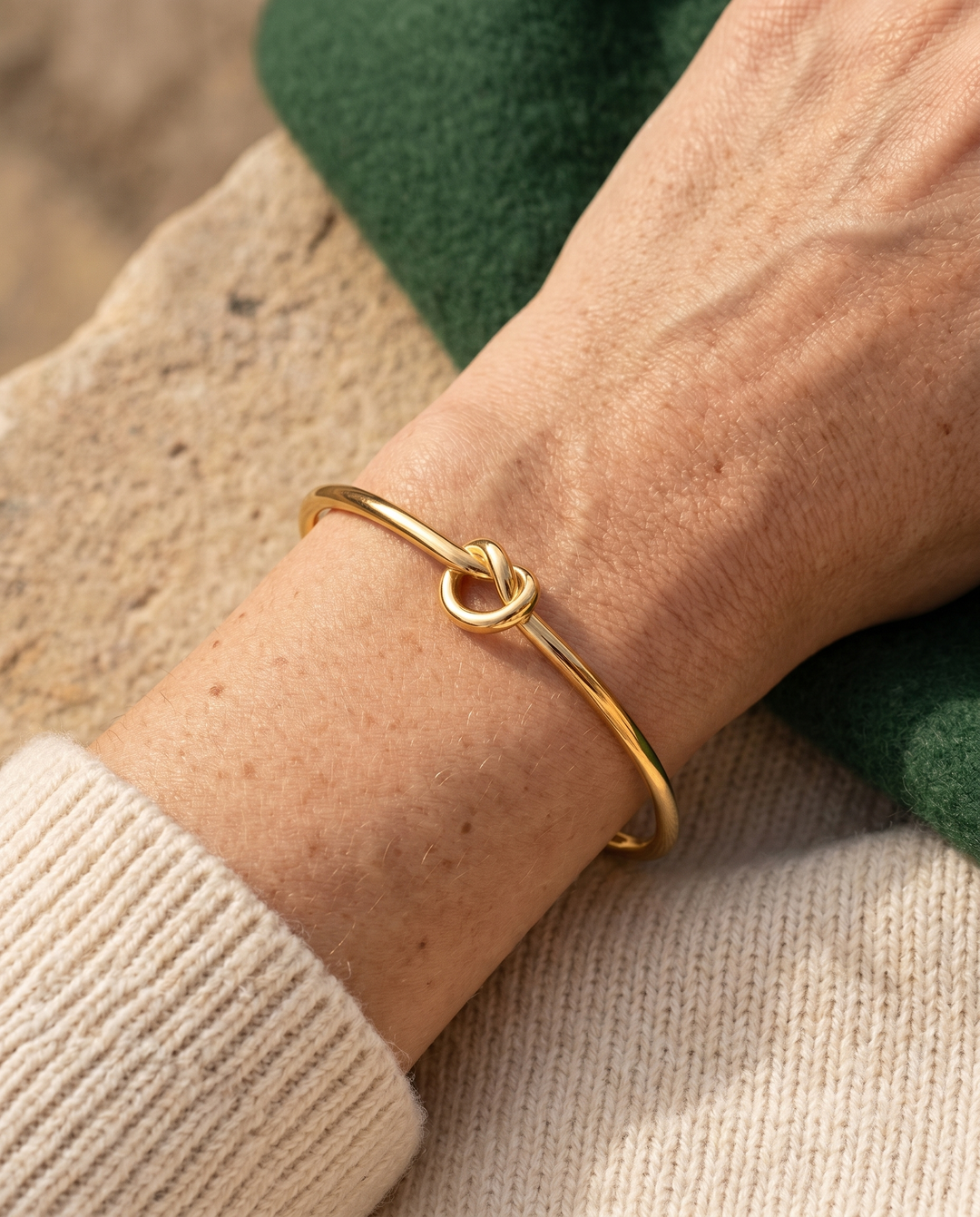 Minimal knot cuff bracelet in gold worn on a woman's wrist